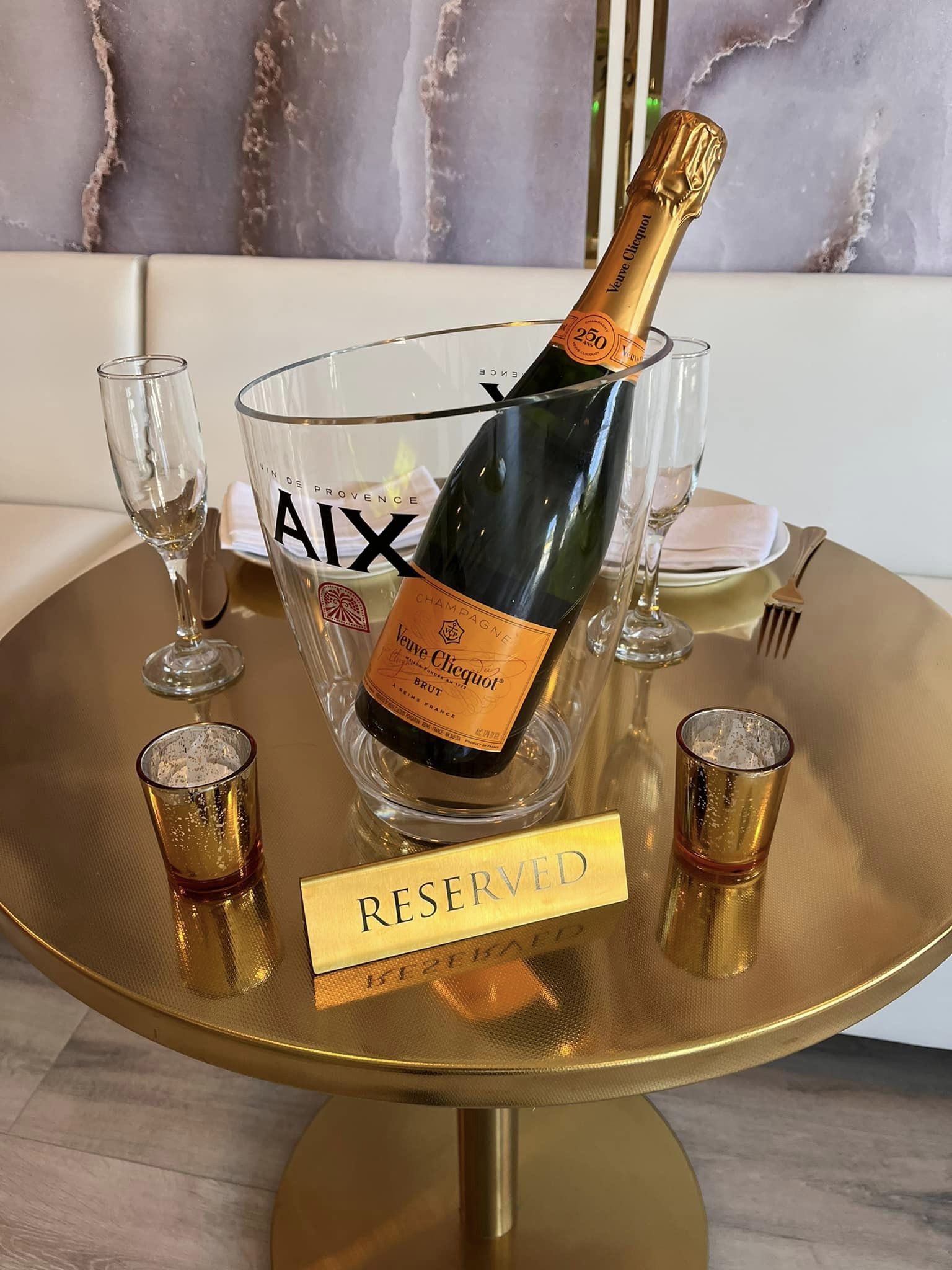 champagne in ice bucket with champagne flutes on a gold table