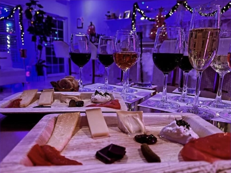  2 cheese boards with glasses of champagne, red and white wine in the background