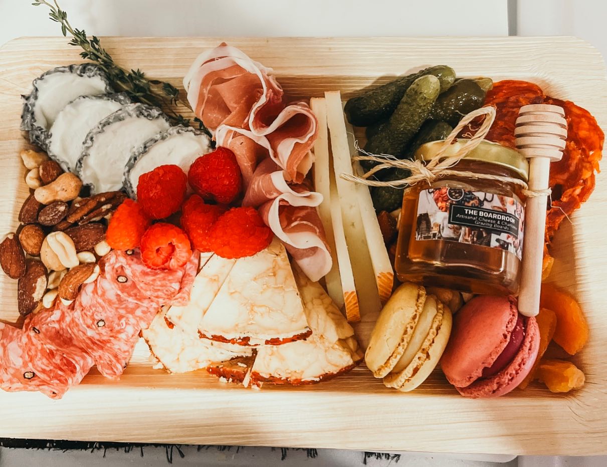 Charcuterie board with meat, cheese, fruit, honey, and macarons